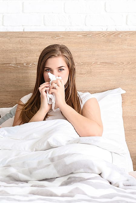Familie im Bett alle schneuzen sich