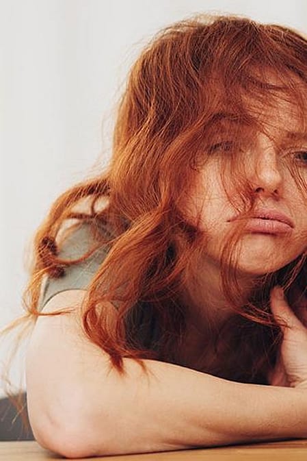 Frau sitzt muede neben einer Tasse Kaffee