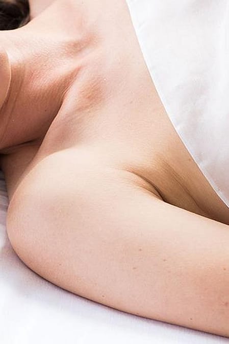 Junge Frau liegt mit geschlossenen Augen im Bett