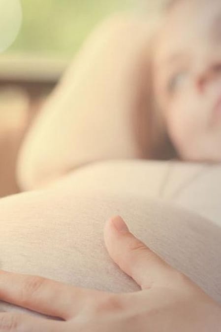 Schwangere Frau liegt auf dem Bett