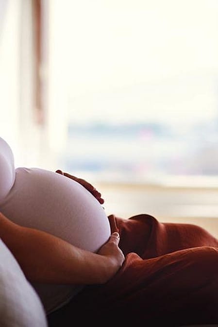 Schwangere legt Hand auf Bauch