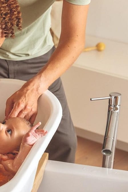 Une mère baigne son bébé avec Weleda