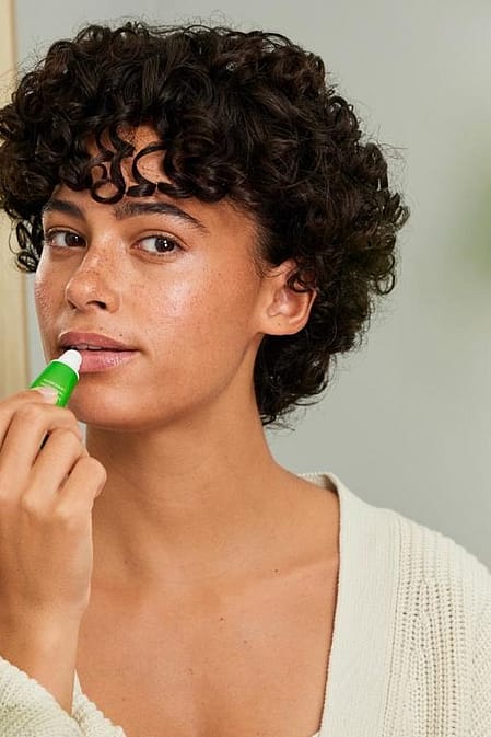 Vrouw doet Skin Food Lip Balm op haar lippen