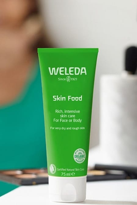 Skin Food 75 ml in the foreground and persons putting on makeup in the background