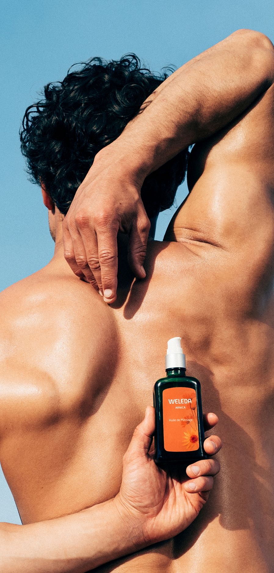 Männlicher Rücken mit Arnika Produkt in den Händen