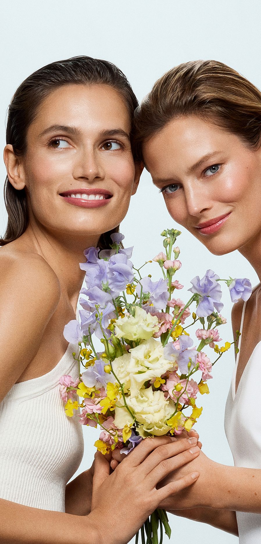 Zwei lachende Frauen mit Blumenstrauß in der Mitte