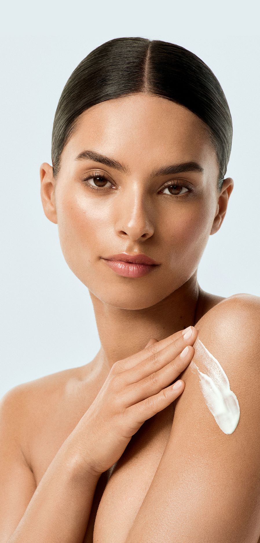 Modella con crema sulla spalla e sfondo bianco