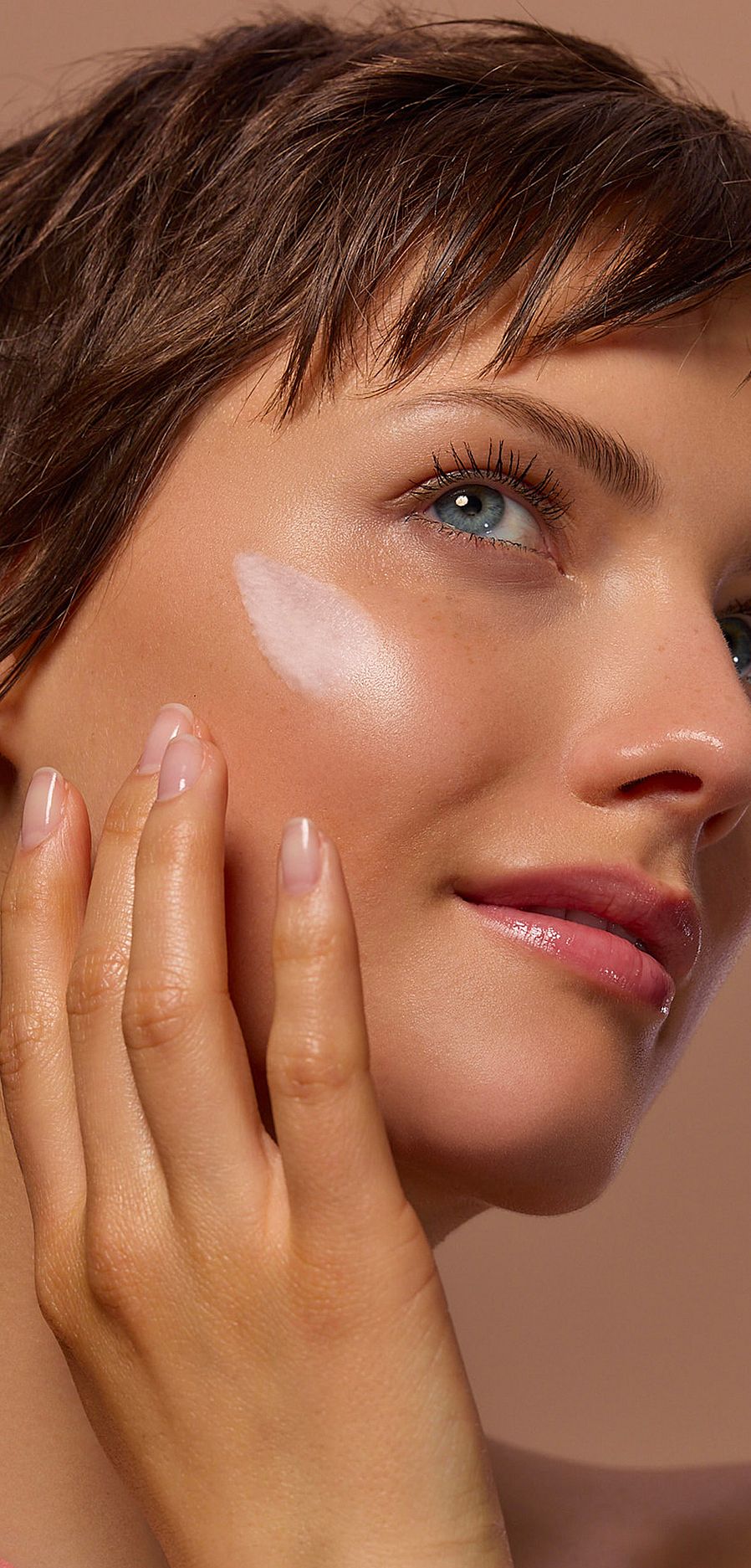 Viso modella che mette crema sulla guancia