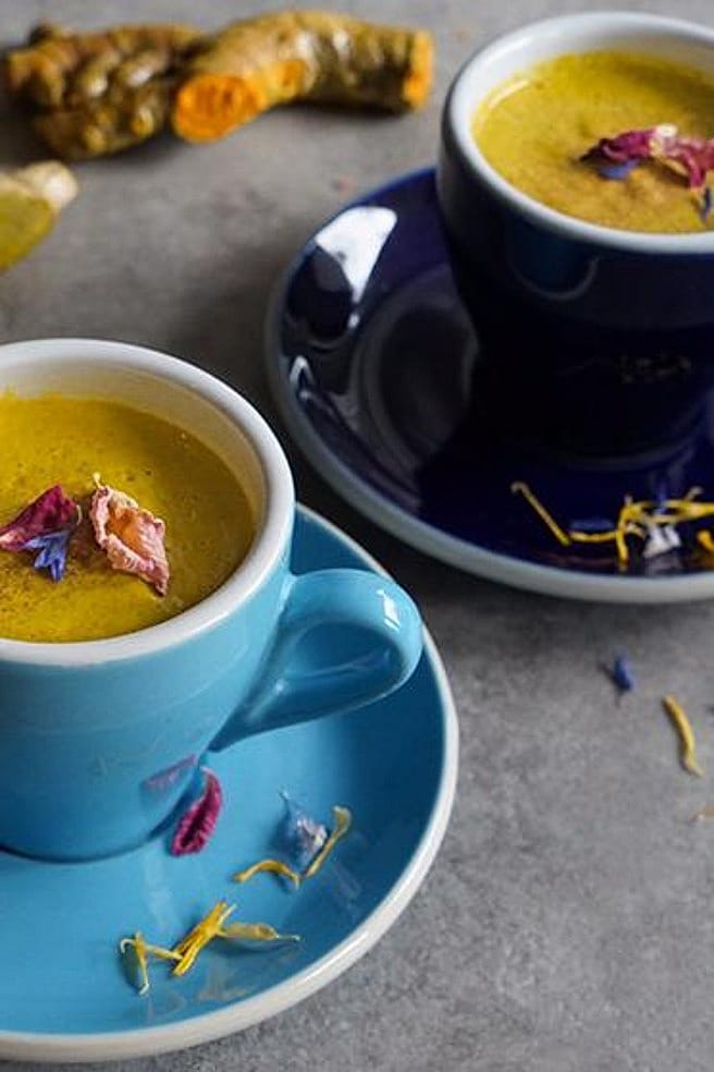 zwei blaue Tassen mit veganer Moonmilk, in Hintergrund liegt eine gelbe Kurkumawurzel