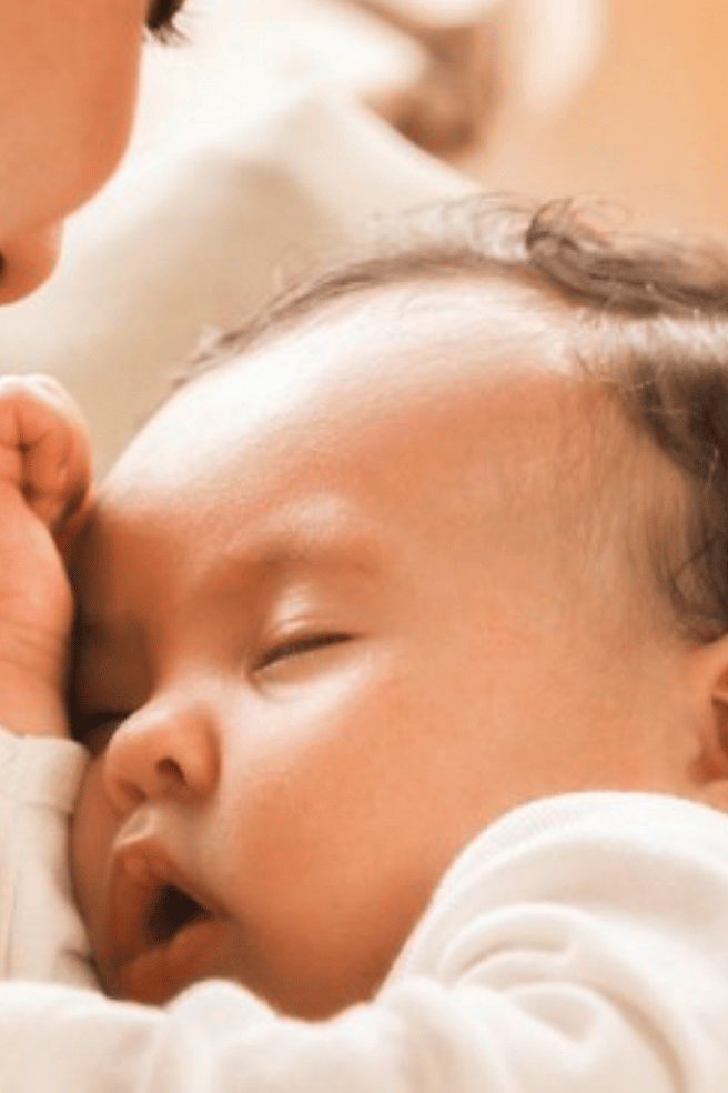mujer sosteniendo a un bebé dormido en los brazos