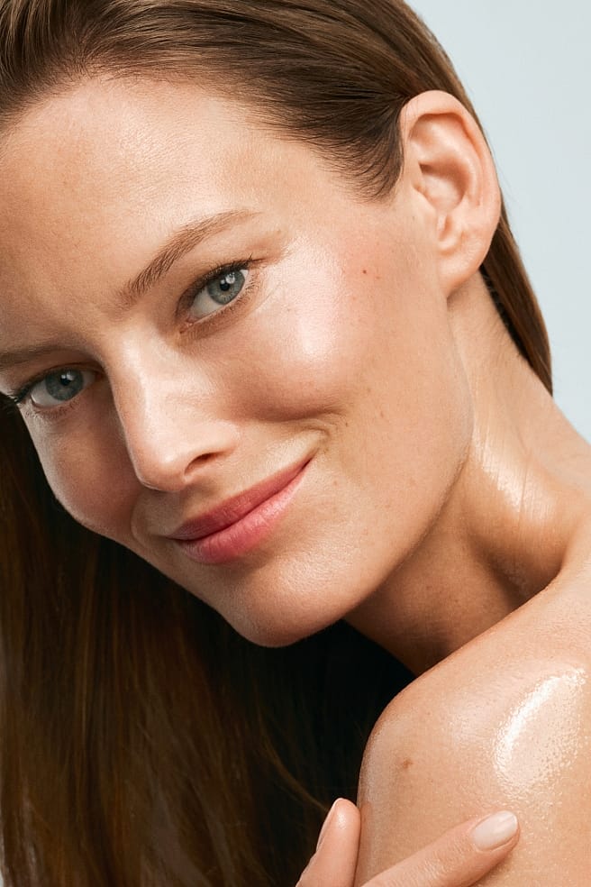 mujer con el hombro con crema mirando a cámara