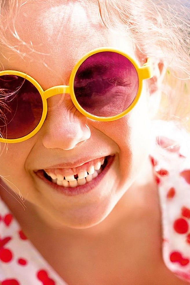 niña con gafas de sol sonriendo
