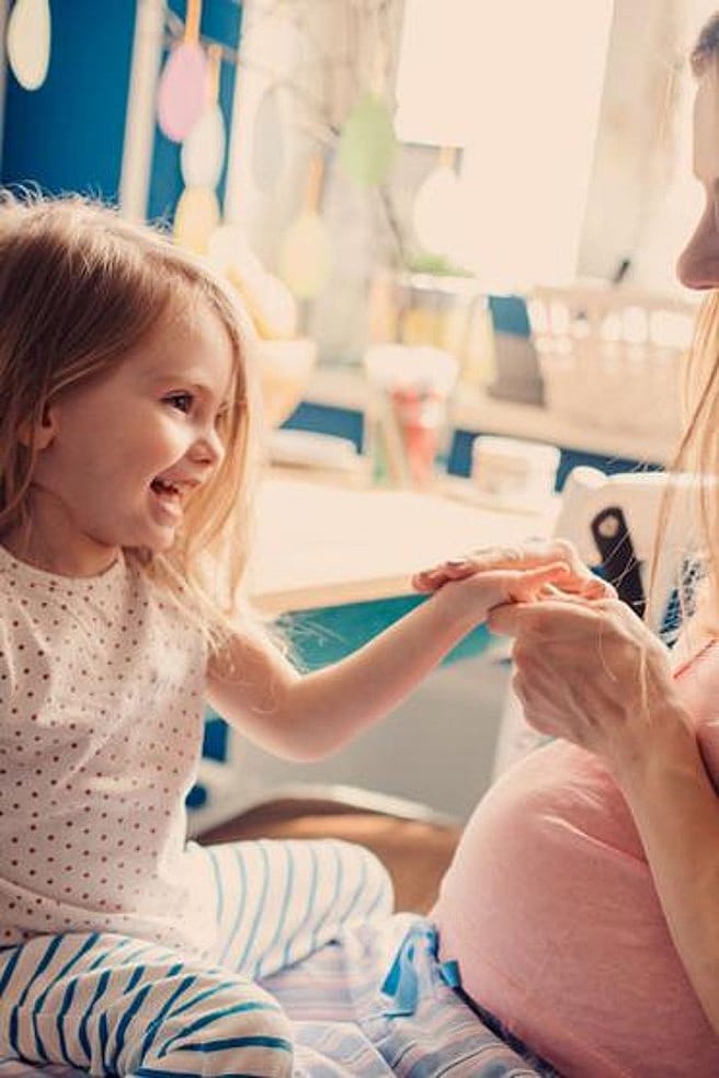 mujer embaraza con su hija sentada en el regazo