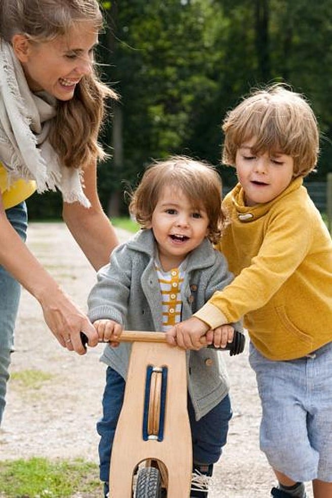 familia ayudando a uno de sus hijos a montar en bici