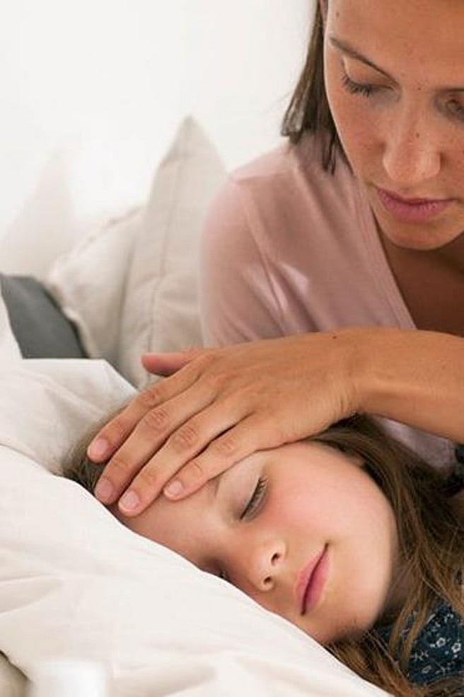 Mama legt schlafendem Kind die Hand auf die Stirn