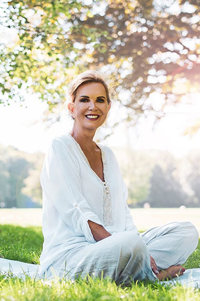 Une femme âgée est assise dans le parc sur une couverture