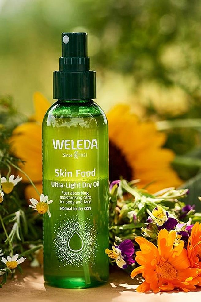Skin Food Ultra-Light Dry Oil entourée de fleurs