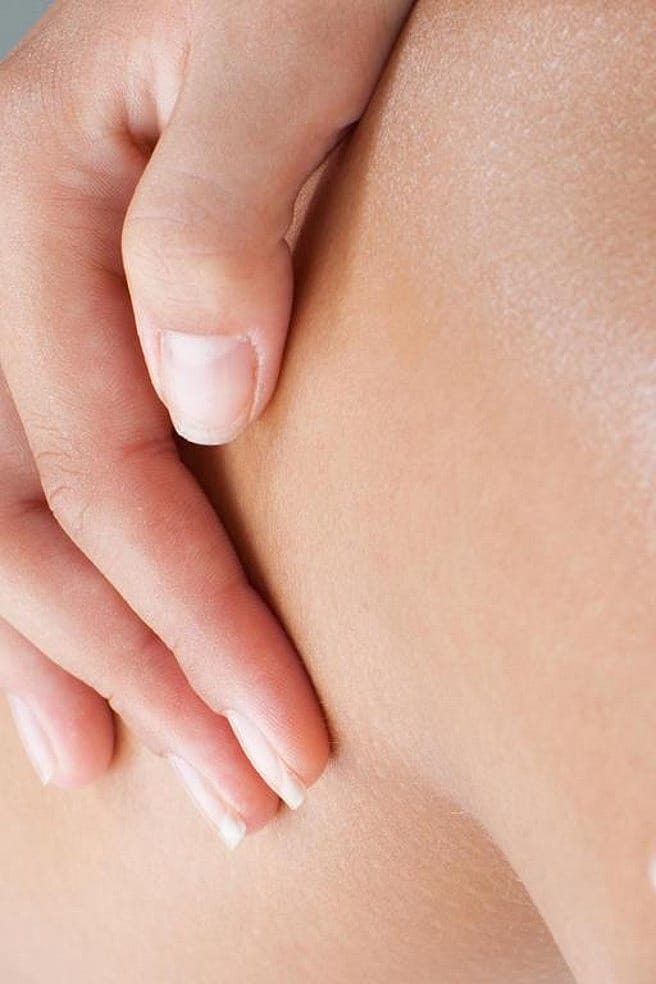 Frau streicht mit der Hand über die Beine