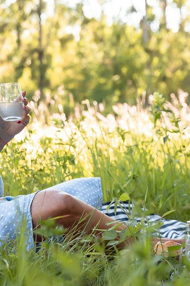 Schwangere Frau im Grass mit Kissen und zu trinken