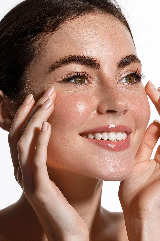 Lächelnde Frau mit Fingerspitzen im Gesicht