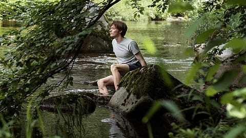 Homme assis sur une pierre dans un lac