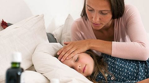 Mama legt schlafendem Kind die Hand auf die Stirn