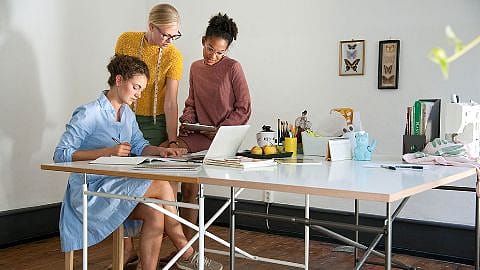 Drei Frauen im Buero am Schreibtisch vor dem Laptop