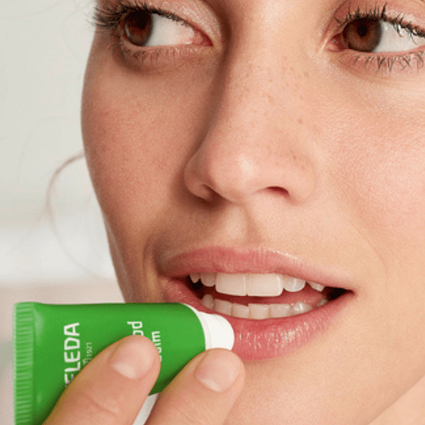 mujer aplicandose el lip balm skin food de weleda