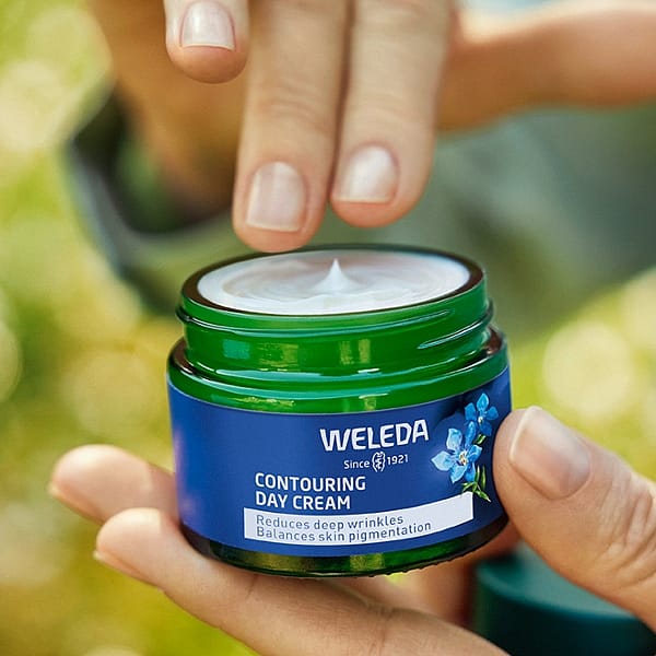 Contouring day cream jar open and held by a woman.