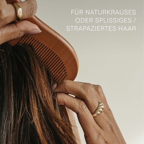 Frau von hinten kämmt sich die Haare. Für naturkrauses oder splissiges / strapaziertes Haar.