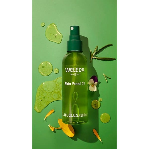 Skin Food Ultra-Light Dry Oil bottle and oil texture surrounded by yellow petals on a green background.