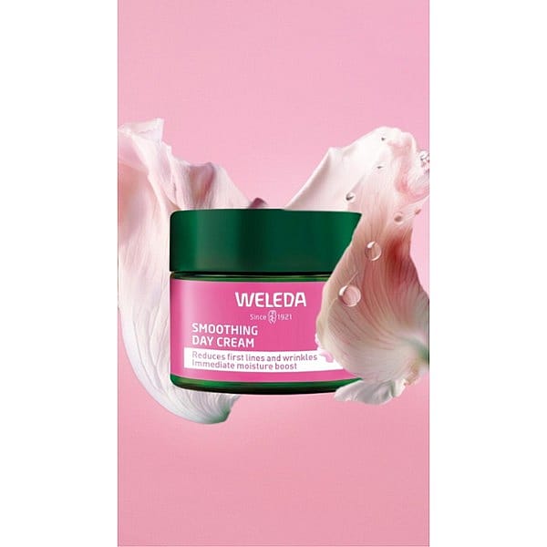 Smoothing Day Cream Wild Rose & White Tea surrounded by a wild rose petal on a pink background.