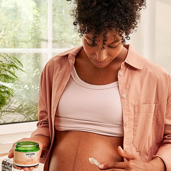 Dark skin woman applying Stretch Mark Body Butter to her pregnant belly.