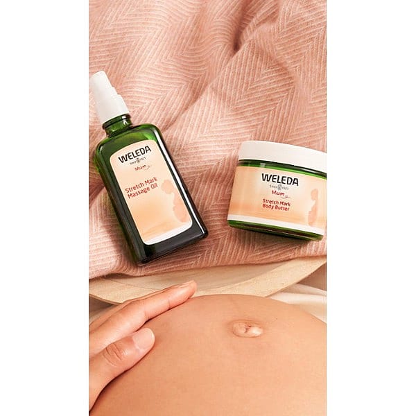 stretch mark massage oil and body butter next to baby belly