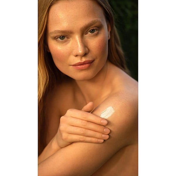 girl sunkissed and applying creme to her body.