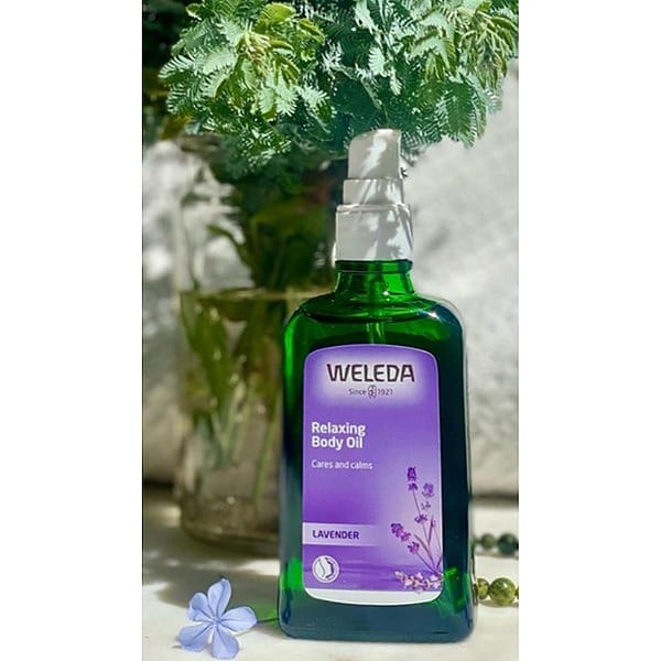 Relaxing Body Oil Lavender infront of a fern in a vase.