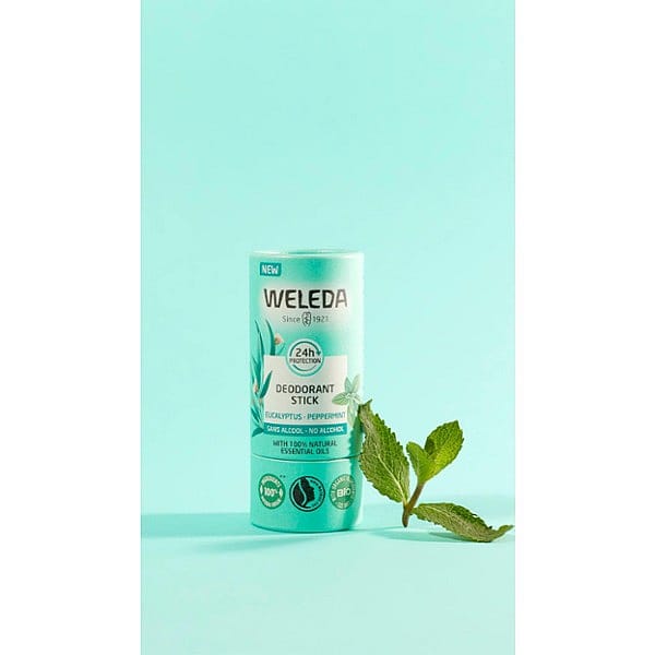 Deodorant Stick Eucalyptus next to peppermint leave, against turquoise background.