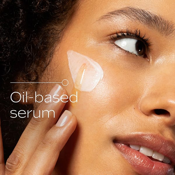 Close-up of a woman applying oil-based serum to her cheek, demonstrating the texture and application of Weleda Extra Rich Omega Serum Booster Drops for glowing, hydrated skin.